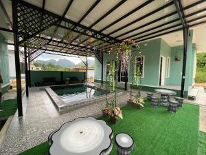 a house with a pool and a patio with green grass at Teratak Sakinah Guest House in Tambun