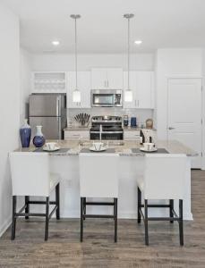 una cocina con armarios blancos y una encimera con sillas blancas en 2 Bedroom Apartment near NAS Jax Base, en Jacksonville