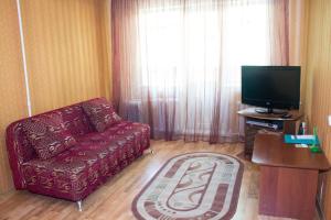 een woonkamer met een rode bank en een flatscreen-tv bij Эдем in Petropavlovsk