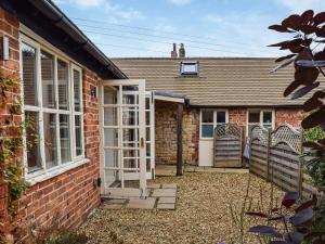 a brick house with a white door and windows at The Stables in Waltham on the Wolds