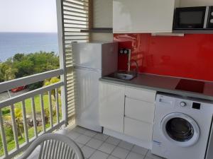 a kitchen with a washing machine and a balcony at Jolie studio vue mer in Le Diamant