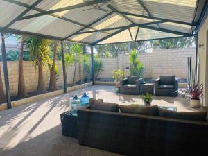 un patio cubierto con sofás, sillas y árboles en Leisurehome en Perth