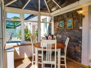 a dining room with a table and chairs and a stone wall at Hilton Farm Steadings in Limekilns