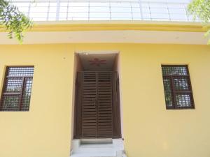 ein gelbes Haus mit einem roten Symbol an der Decke in der Unterkunft OYO Hotel Pari in Greater Noida