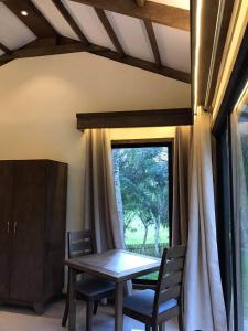 ein Esszimmer mit einem Tisch, Stühlen und einem Fenster in der Unterkunft Forest garden residence in Bilar