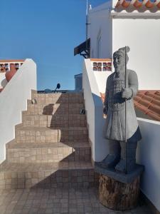 una estatua de Aaraoh en el lado de un edificio con escaleras en Lar Dos Guerreiros, en Vila Nova de Milfontes