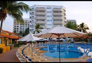 une piscine avec des chaises et des parasols et un bâtiment dans l'établissement El mejor departamento a la orilla del mar, à Ixtapa