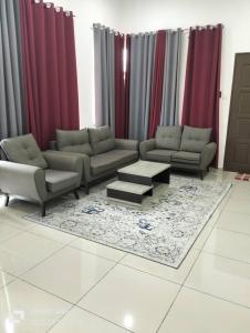 uma sala de estar com sofás, uma mesa e cortinas vermelhas em Homestay Gua Musang em Gua Musang