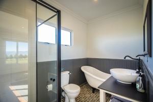 a bathroom with a tub and a toilet and a sink at Dragons Landing Cottage in Underberg