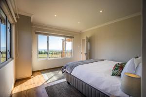 a bedroom with a bed and a large window at Dragons Landing Cottage in Underberg