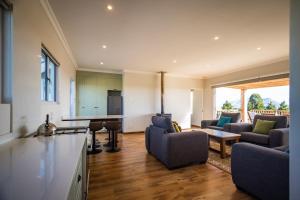 cocina y sala de estar con sofás y mesa en Dragons Landing Cottage en Underberg