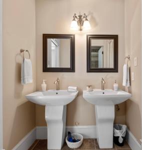 2 lavabos blancos en un baño con 2 espejos en Executive pet friendly lower suite with ocean view, en Ladysmith