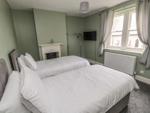 two beds in a green room with a fireplace at Prudhoe Cottage in Prudhoe