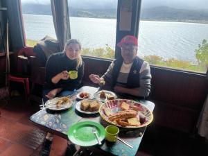 a man and a woman sitting at a table with food at Madervillhospedaje in Aquitania