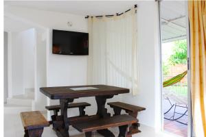 a table and two benches in a room with a tv at Villa Alejandra in Girardot