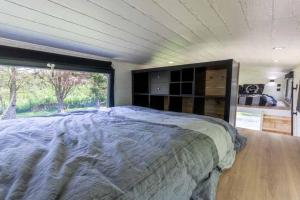 a bedroom with a large bed and a large window at Mini maison Tiny house 6 per 3800m2 jardin Jacuzzi in Pontault-Combault