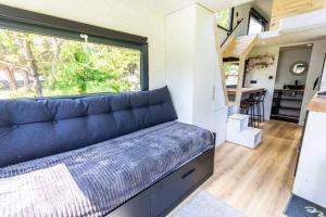 a living room with a blue couch in a tiny house at Mini maison Tiny house 6 per 3800m2 jardin Jacuzzi in Pontault-Combault
