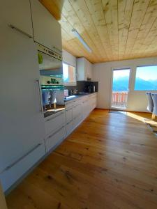 a large kitchen with white cabinets and wood floors at Chalet Matterhornsicht in Naters