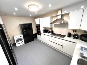 a kitchen with a black refrigerator and a washing machine at Nines of Elegance At Castle Road in Birmingham