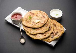 a plate with a stack of naan bread and a spoon at Hotel Ganga Ashoka - Rishikesh in Rishīkesh