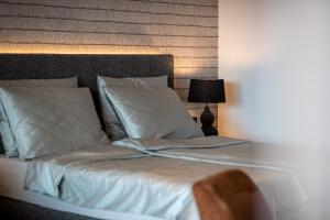 Cama con sábanas blancas y almohadas junto a una lámpara en Hotel Finkenhof - Feel at home, en Scena