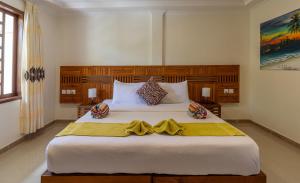 a bedroom with a large white bed with a yellow blanket at Kamadhoo Inn in Baa Atoll