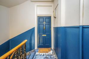 a blue door in a room with a stair case at Stunning 3 Bdr Apartment 5 Min From Haymarket in Edinburgh