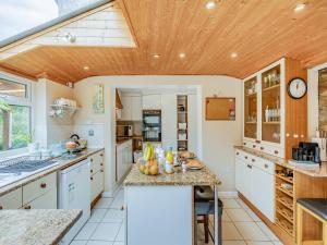 a kitchen with white cabinets and a wooden ceiling at Oak Villa in Cinderford