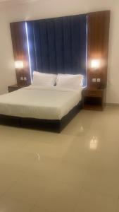 Una cama en una habitación con dos luces en los lados. en ريف الشاطئ للشقق الفندقية en Dammam