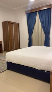 a bedroom with a large bed with blue curtains at ريف الشاطئ للشقق الفندقية in Dammam