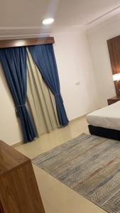 a bedroom with a bed and a blue curtain at ريف الشاطئ للشقق الفندقية in Dammam