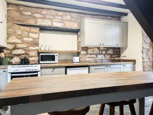 a kitchen with white cabinets and a wooden table at Meadow View Cottage in Highpeak Junction