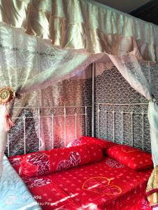 a bed with red pillows on top of it at Homestay Teratak Kayu kota Aur in Kepala Batas
