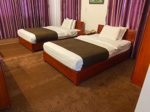 2 camas en una habitación de hotel con cortinas moradas en Bao Son Hotel en Ninh Lão