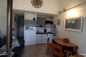Petit chalet dans résidence في فون-رومو-أوديللو-فيا: مطبخ مع طاولة وساعة على الحائط