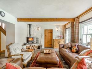 a living room with a leather couch and a fireplace at The Coach House - Uk45027 in Gilwern