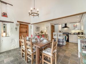 Il comprend une cuisine et une salle à manger avec une table et des chaises en bois. dans l'établissement The Coach House - Uk45027, à Gilwern