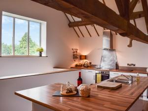 cocina con encimera de madera y fregadero en The Barn, en Nantwich