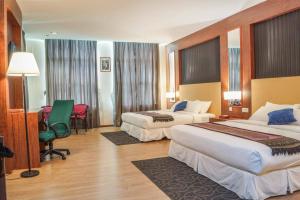 Kampong Batu MaungにあるHotel Pen Mutiaraのベッド2台とデスクが備わるホテルルームです。