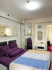 a bedroom with a large bed with purple pillows at Apartemen kalibata city By Alia Property in Jakarta