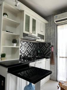a kitchen with white cabinets and a black counter top at Apartemen kalibata city By Alia Property in Jakarta