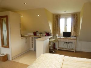 a bedroom with a bed and a kitchen with a desk at Glen House Annexe in Bourne