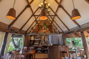 a dining room with wooden tables and chairs and large windows at Le Charcoa Hotel in Chiang Mai