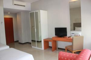 um quarto com uma secretária, uma televisão e uma cama em Javein Griyadi Hotel em Jakarta
