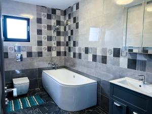 a bathroom with a tub and a sink and a toilet at Casa Maya in Curtea de Argeş