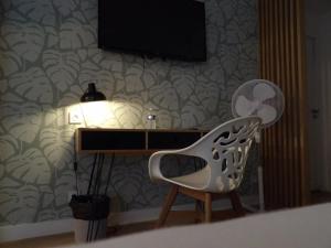 a chair sitting next to a desk with a television at Hotel le Broceliande - Sure Hotel Collection by Best Western in Bédée