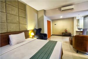 um quarto de hotel com uma cama e uma cadeira em Javein Griyadi Hotel em Jakarta