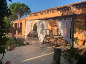 d'une terrasse avec des rideaux blancs, une table et des chaises. dans l'établissement Chambre d’hôtes Mazet Les Abadies, à Saint-Félix-de-Lodez