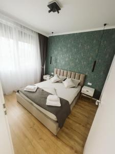1 dormitorio con cama y pared verde en Sika Majestic Apartment en Arad