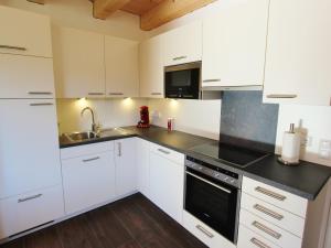 a kitchen with white cabinets and black counter tops at Chalet in ski area in Koetschach-Mauthen in Kötschach